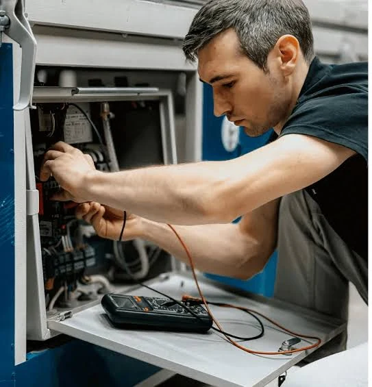 Technician inspecting controls inside a heating system cabinet