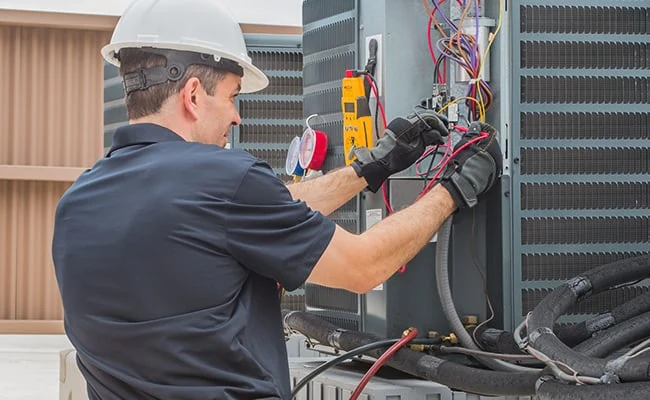 Technician checking electrical components in an outdoor HVAC cabinet